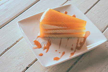 木制桌子上白盘子的橙色蛋糕图片