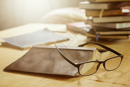 木制桌子上有书的眼镜 柔软的焦点 明亮的阳光 古老的音调图片
