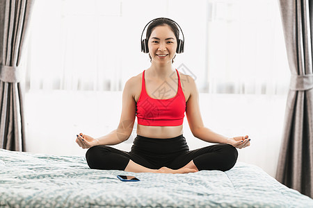 亚裔妇女在家里做瑜伽 在Cov的时候睡在卧室的床上图片