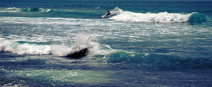 太阳光灯冲浪者乘着浮板蓝海水随心所欲蓝色男人海浪假期旅行运动乐趣行动设施冲浪图片