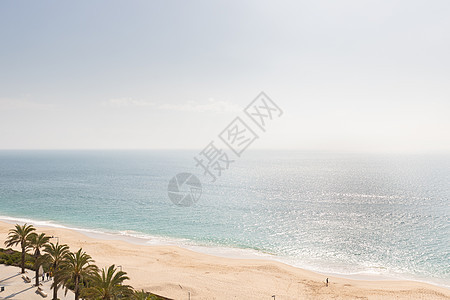 葡萄牙塞辛布拉海滩的海风 有棕榈树海滩橙子风景海洋太阳天空蓝色石头海岸线建筑物图片