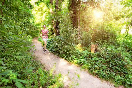 跑步运动员在森林中奔跑的年长女子公园树木效果女士小路森林赛跑者活动慢跑人行道背景