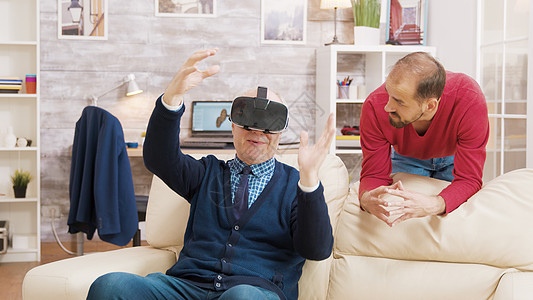 侄女教他祖父如何使用虚拟现实头耳机帮助视频游戏男人模拟乐趣惊愕技术眼镜退休图片