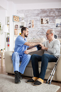 在养老院接受血压护理的年轻男医生药品疾病卫生压力病人男性护士血压治疗退休图片