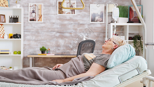 在养老院躺在医院床上的老太太女士成人公寓诊所老年午睡休息药品医生床头图片