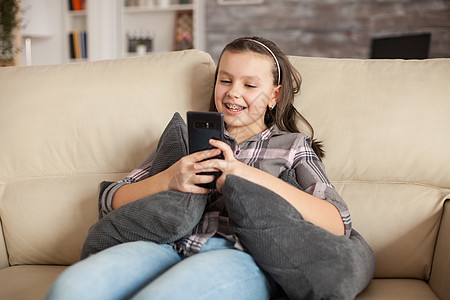 在客厅沙发上坐着带牙套的少女青春期写作细胞短信女学生孩子女士白色手机童年图片