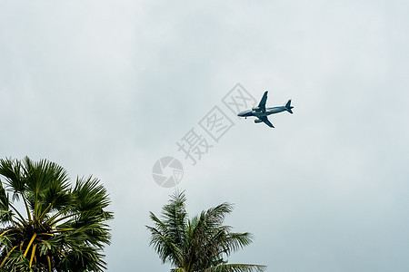 飞机在云层中飞行 准备降落在一个热带岛屿上空速技术阳光客机喷射翅膀商业喷气蓝色太阳图片