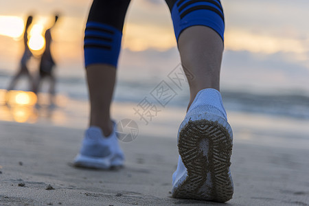 日出时在沙滩上跑的女子 在鞋上紧贴女孩慢跑者天空训练跑步赛跑者海岸运动员护理阳光图片