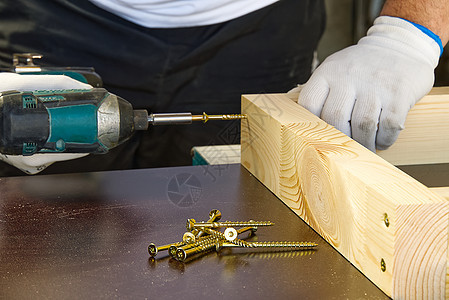 木匠 一个男人用无绳螺丝刀工作 使用无绳电钻钻孔并拧紧螺钉 在木工车间处理木材生产木匠铺程序职业屋顶力量地板旋转飞机机器图片