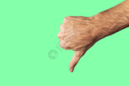 在绿色背景上孤立的拇指向下手势图片