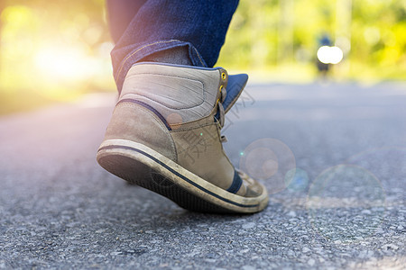 穿着牛仔裤和运动运动鞋的人在路上行走靴子皮革沥青鞋类雏菊日落女士成功活动街道图片