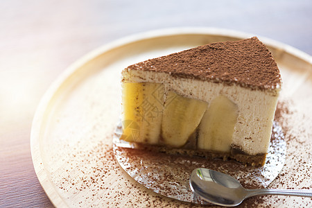 木板上涂有巧克力粉末的香蕉派食物白色馅饼盘子装饰糕点甜点黑色蛋糕奶油图片