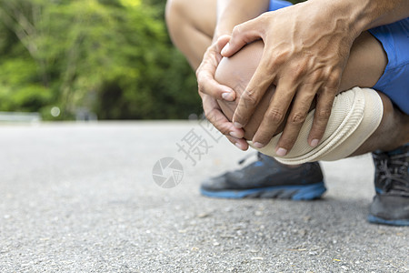 穿蓝短裤的人跑后用手抓膝盖训练肌腱韧带身体运动员肌肉髌骨公园痛苦跑步图片