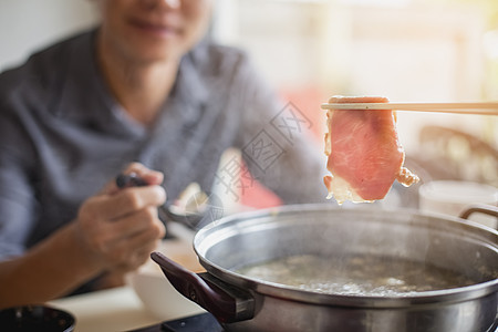 英俊男人把肉和猪肉 滑到热锅里烧烤盘子菜单午餐面条美食海鲜烹饪餐厅牛肉图片