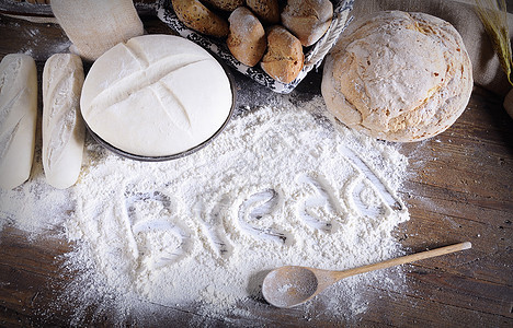 散落在木制桌上的面粉上写着单词“面包”图片