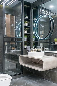 优雅的白色水槽站在灰色的架子上 上面挂着一面圆镜 黑色和灰色大理石浴室内饰图片
