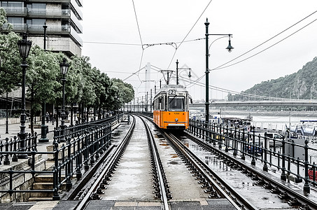 2辆橙色电车从贝尔格莱德堤岸附近的Erzhebet桥沿多瑙河通过 匈牙利布达佩斯图片