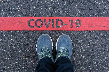 身穿运动鞋的男子站在红线旁边 有CCOVID-19文本图片