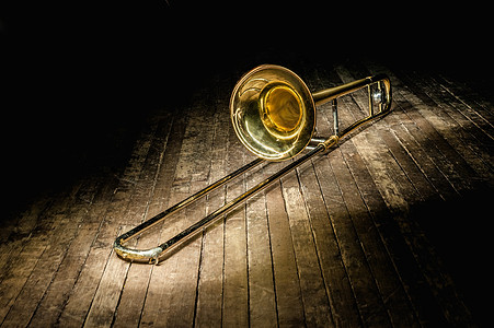 金黄铜乐器长号 位于光线中的深褐色木制舞台上图片