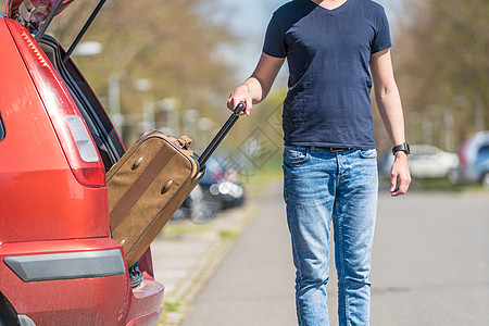 这名青年男子从汽车后备箱拖走行李图片