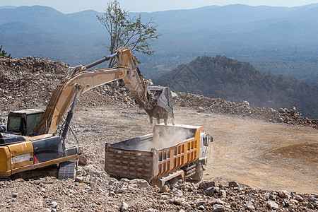 黄色挖土机在煤矿用石头填满垃圾车土壤金属场地机械岩石卡车土方建筑挖掘地球图片