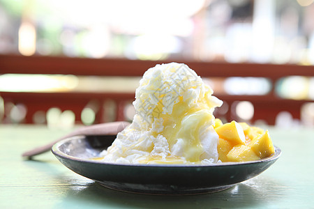 与新鲜芒果一起的雪冰甜点牛奶果味美食奶油勺子盘子胡子水果白色糖浆图片