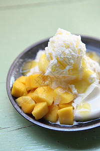 与新鲜芒果一起的雪冰甜点食物糖浆胡子水果果味勺子奶油美食白色盘子图片