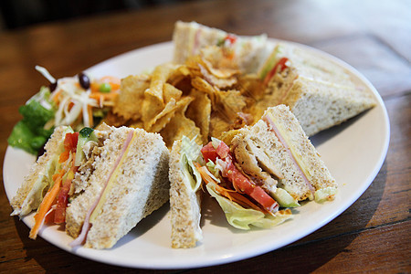 带有木本背景的俱乐部三明治火腿杯子蔬菜餐厅木头筹码照片咖啡面包午餐图片
