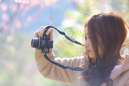 美丽的年轻女子拍照 与开花樱花S背景图片