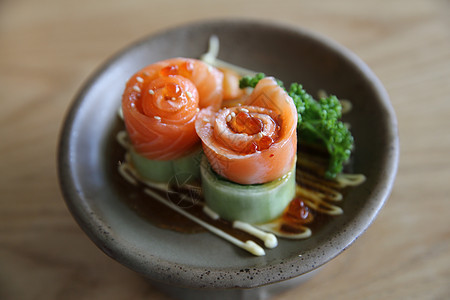 含黄瓜的鲑鱼生西米和木头上的黄瓜盘子筷子鱼片蔬菜橙子寿司海鲜餐厅桌子红色图片