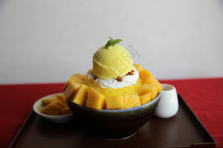 与新鲜芒果一起的雪冰甜点美食白色水果糖浆盘子食物勺子牛奶奶油乳白色图片