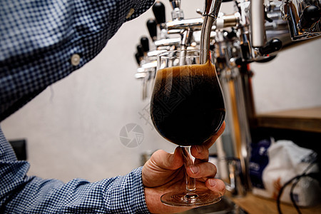 酒保在酒吧里从水龙头上倒新的黑啤酒派对餐厅工艺调酒师食物酿造啤酒厂服务泡沫酒精图片