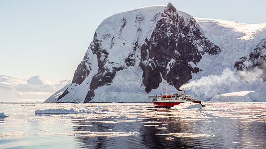 红色游轮蒸汽船漂流在冰山之间 岩石巨大场景旅行冰川旅游荒野气候勘探编队海洋巡航图片