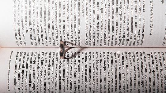 在一本书的两页之间的结婚环 与阳光相交 铸造了一颗心形的阴影图片