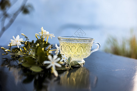 印度茉莉花 Juhi或在木质表面的近乎茶叶杯子陶瓷茶点树叶桌子咖啡店植物三叶草茉莉叶子图片