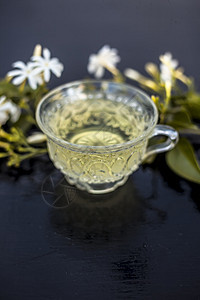 印度茉莉花 Juhi或在木质表面的近乎茶叶杯子三叶草茶包液体制品树叶叶子茶点食物茉莉图片