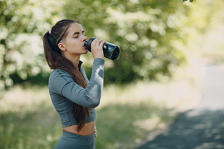 运动的女性在公园喝瓶装水图片