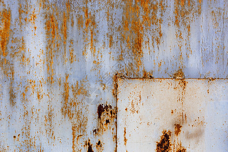生锈的平面实心金属板表面 有白色和浅蓝色油漆的残留物 角落有矩形补丁图片