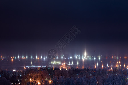 带有光柱气现象的冬季寒夜城市风景地平线气氛森林射线星星薄雾太阳光束气象摄影图片