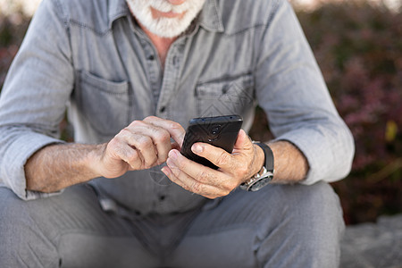 老年人在智能手机上打短讯工具退休互联网成人技术电话老年男性男人图片