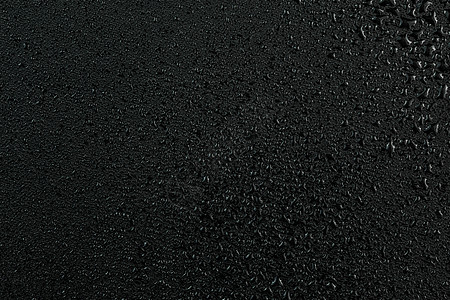 扁平黑色橡胶表面上水滴的深色抽象背景图片