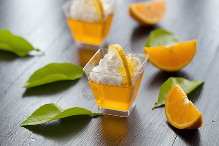杯子中的橘子果冻加奶油和橙汁叶子美食橙子食物明胶绿色小吃白色黄色果味图片