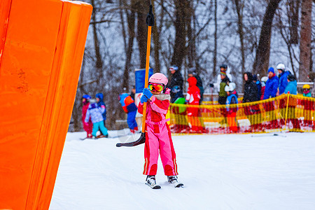 在滑雪电梯里穿着滑雪西装的小女孩图片