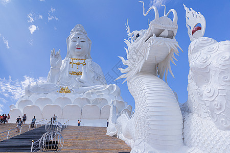 在泰国清莱怀普拉江寺 蓝天和云空的关燕雕像和龙雕像图片