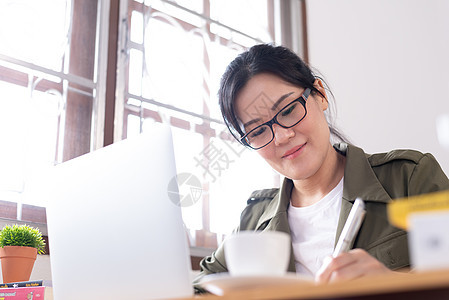 现代亚洲年轻女性在家工作 笑声商业写作咖啡电话房间女孩电脑书架眼镜商务图片