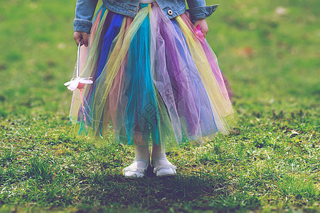 小女孩穿着多彩的Tutu裙 在绿草上站立高清图片