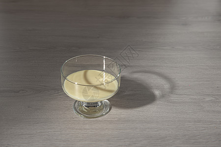 以木制背景的透明玻璃碗中冷凝牛奶茶匙糖果奶油厨房香草木头食物漩涡勺子奶制品图片
