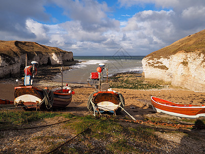 在海滩上等待潮水与白悬崖的 富彩多彩的红白渔船图片