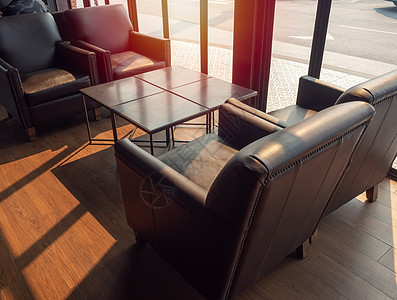 棕色皮面沙发 玻璃附近的木地板上有木制桌酒店工作室地面椅子奢华餐厅座位皮革公寓窗户图片