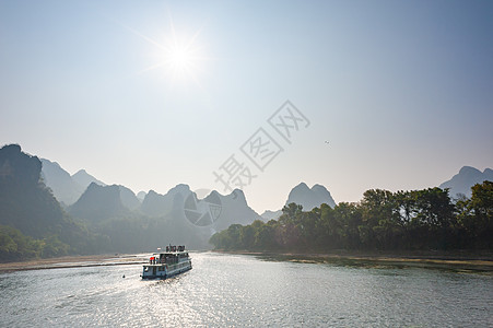 乘Li河巡航的船在桂林对太阳和喀斯山形成山脉风景图片